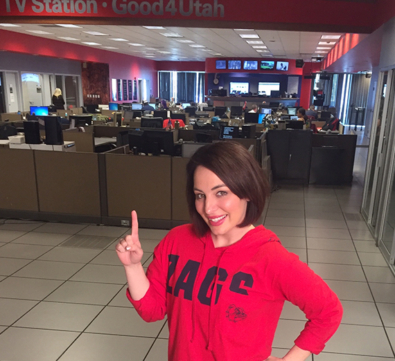 Женщина в выпускном колпаке и мантии улыбается в камеру